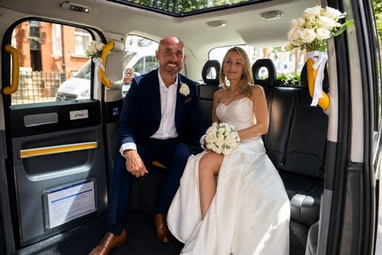 Newlyweds seated together inside the electric TXE wedding taxi