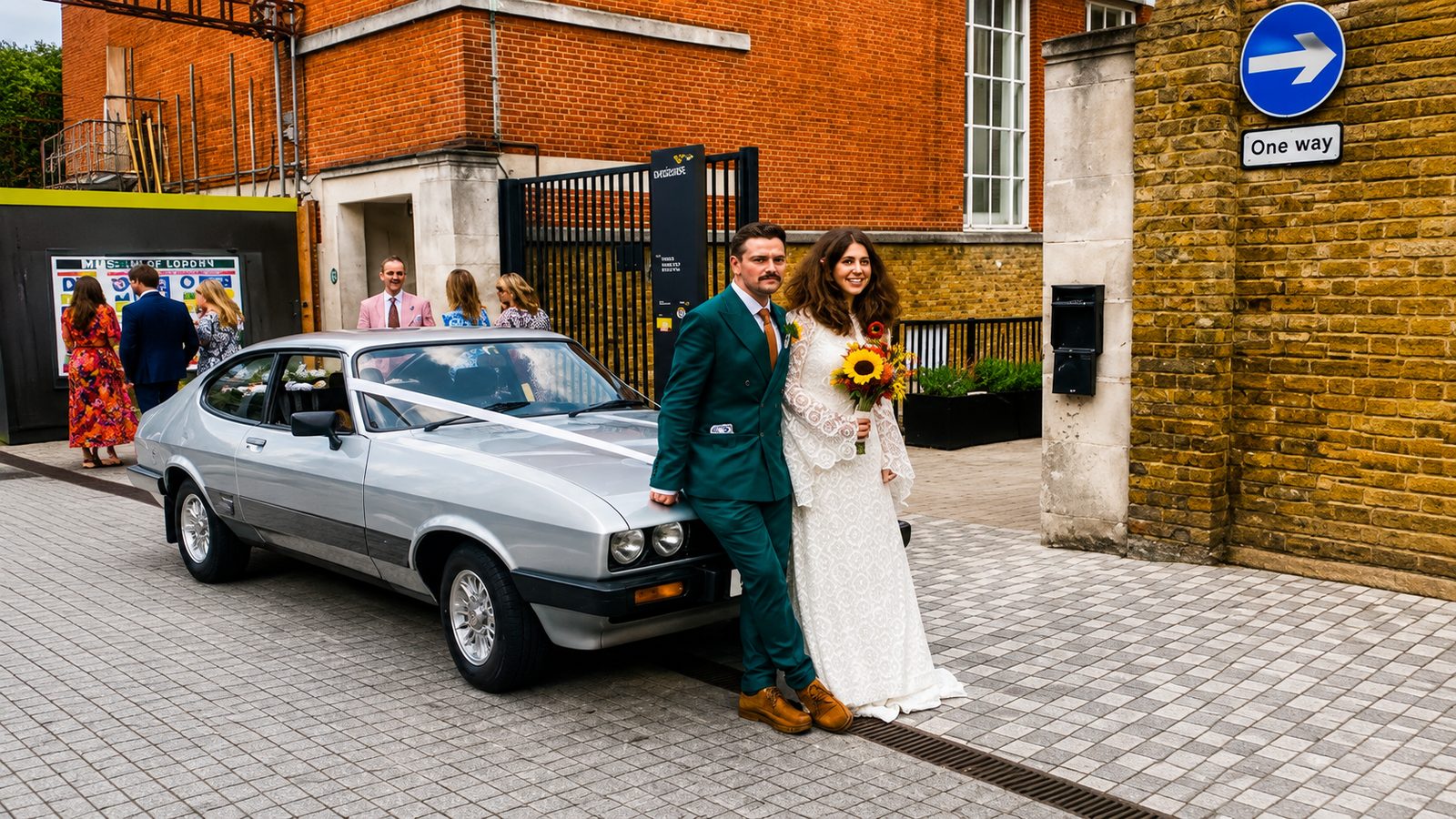 Newlyweds beside the silver Ford Capri 3.0 S outside the Museum of London